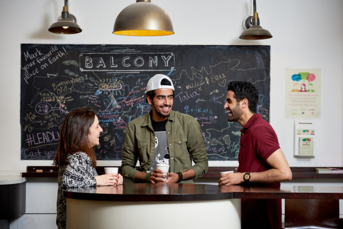 Three students laughing and talking in a cafe