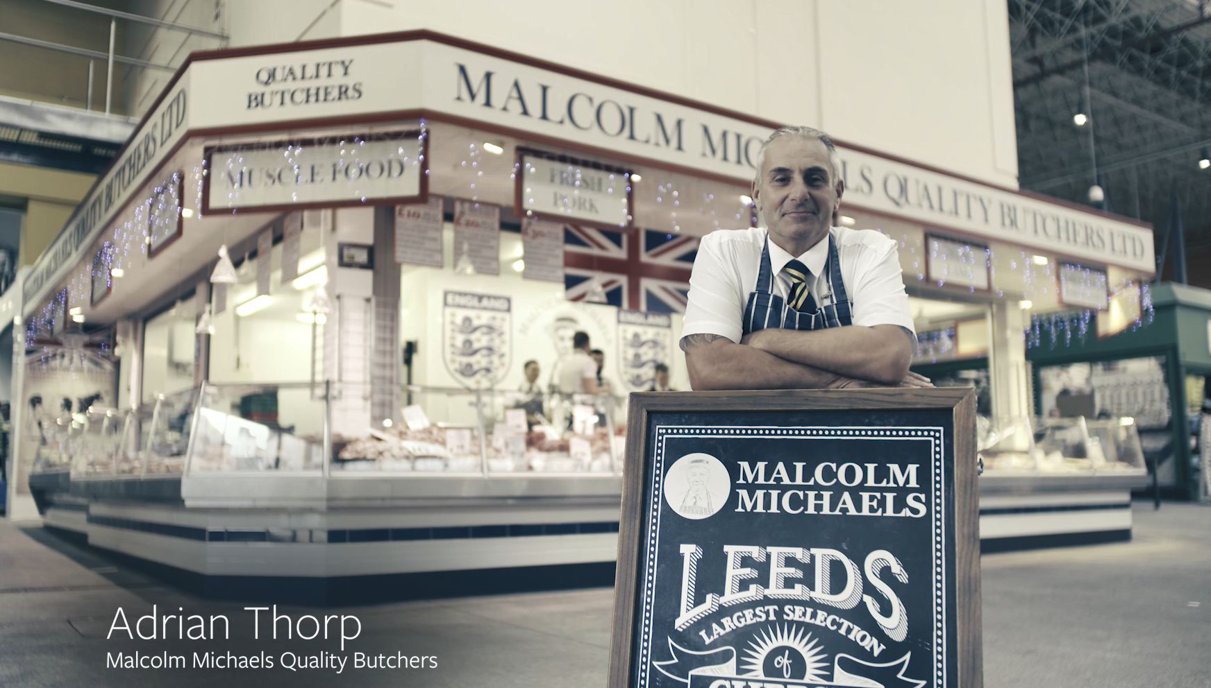 Butcher standing by market stall sign