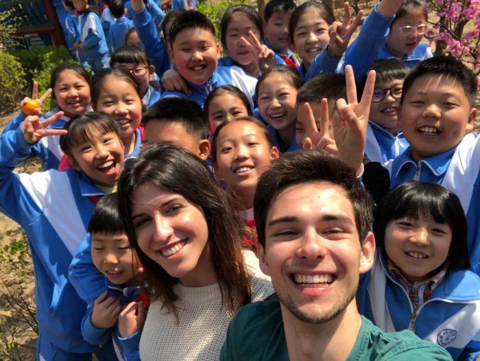 Two non-Chinese students taking a selfie with a group of Chinese schoolchildren