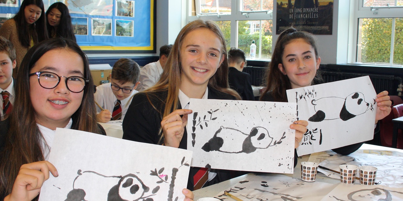 School students showing off their Chinese panda paintings