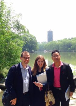 Three people smiling in front of a Chinese lake