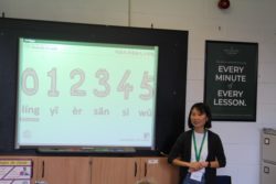 Chinese teacher standing by the board, which says 0-5 in Chinese