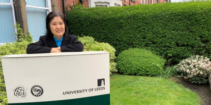 Chinese woman standing behind the Business Confucius Institute sign