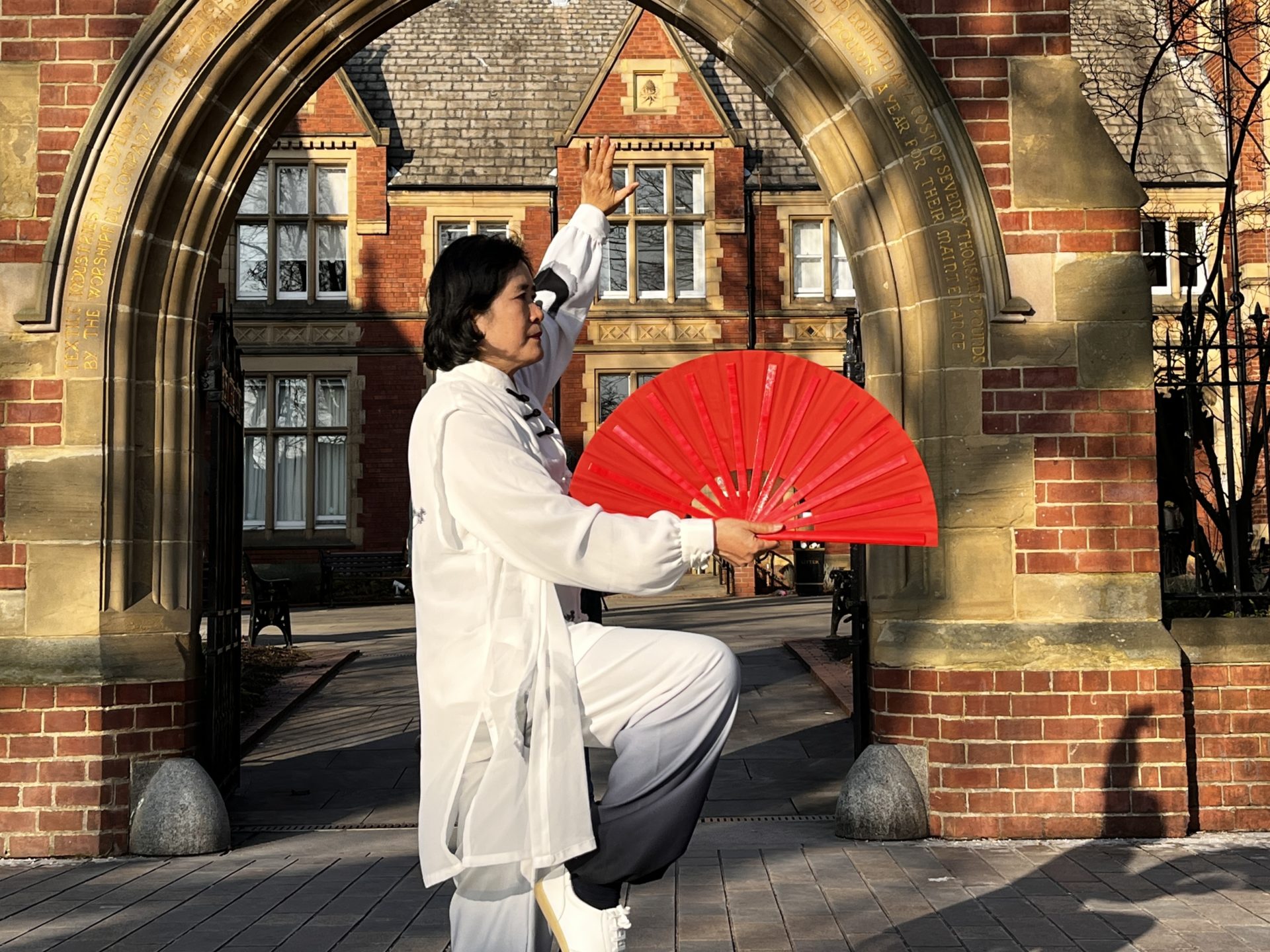 Woman in a martial arts pose holding a red fan