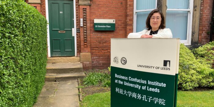 Chinese woman standing behind the sign outside the Business Confucius Institute office