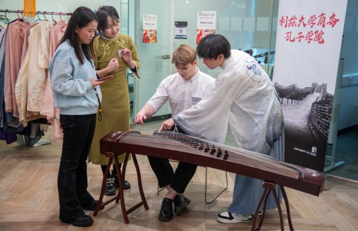 Four people gather round the guzheng